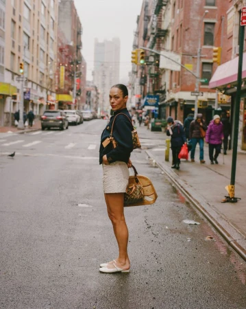 Model Carliane Paixao standing on an urban street holding a monogram handbag for ODDA Magazine editorial 1896, and The Rest is History.
