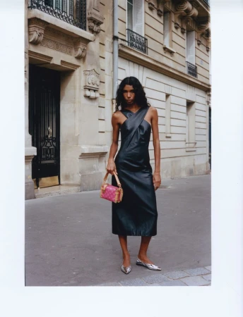 Model Carliane Paixao wearing a black leather dress and holding a pink handbag on a Parisian street for ODDA Magazine.