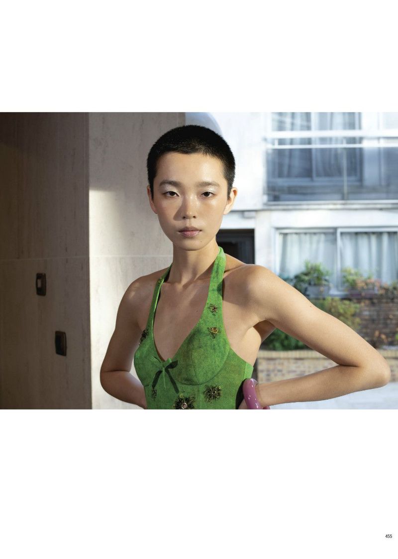 Model with short dark hair wearing a green halter top outdoors against an architectural background for Pop Magazine editorial