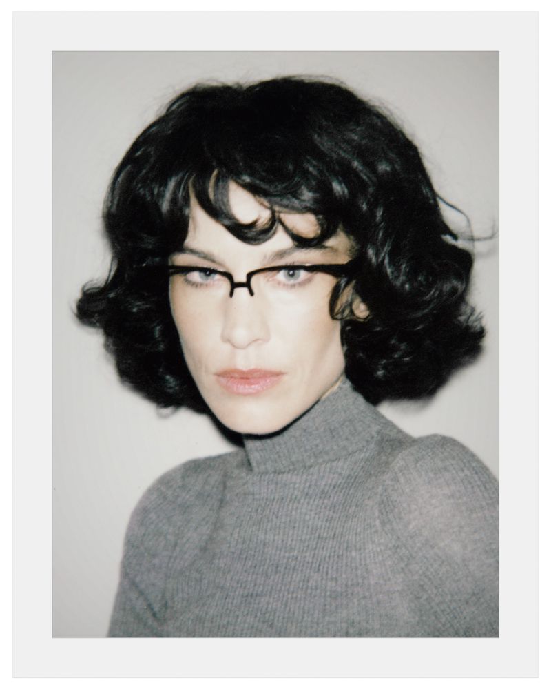 Portrait of Alexa Chung wearing black glasses and grey turtleneck against a white background