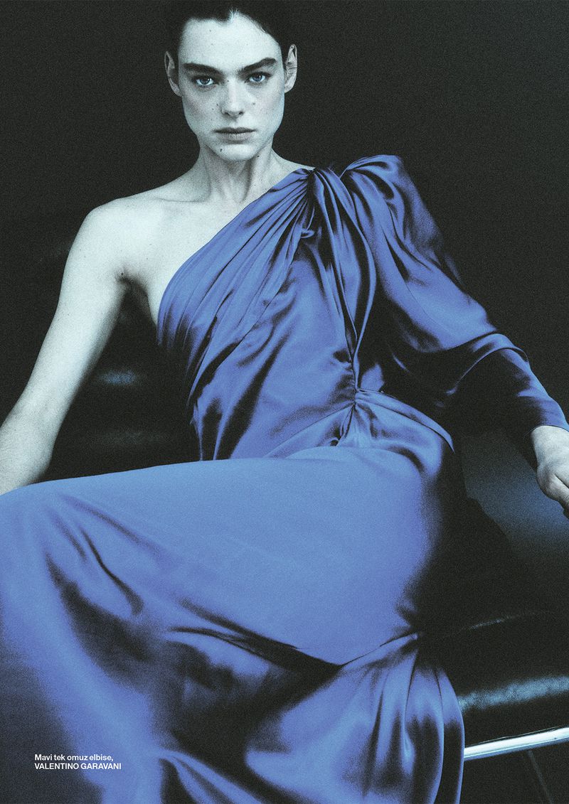 Model Lea Haesaert wearing a royal blue one-shoulder satin dress seated against a dark background for Numéro Istanbul.