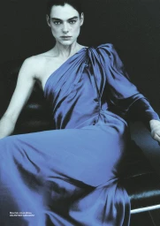 Model Lea Haesaert wearing a royal blue one-shoulder satin dress seated against a dark background for Numéro Istanbul.