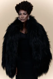 Venus Williams wearing a large black faux fur coat and glittering earrings against a neutral studio backdrop.