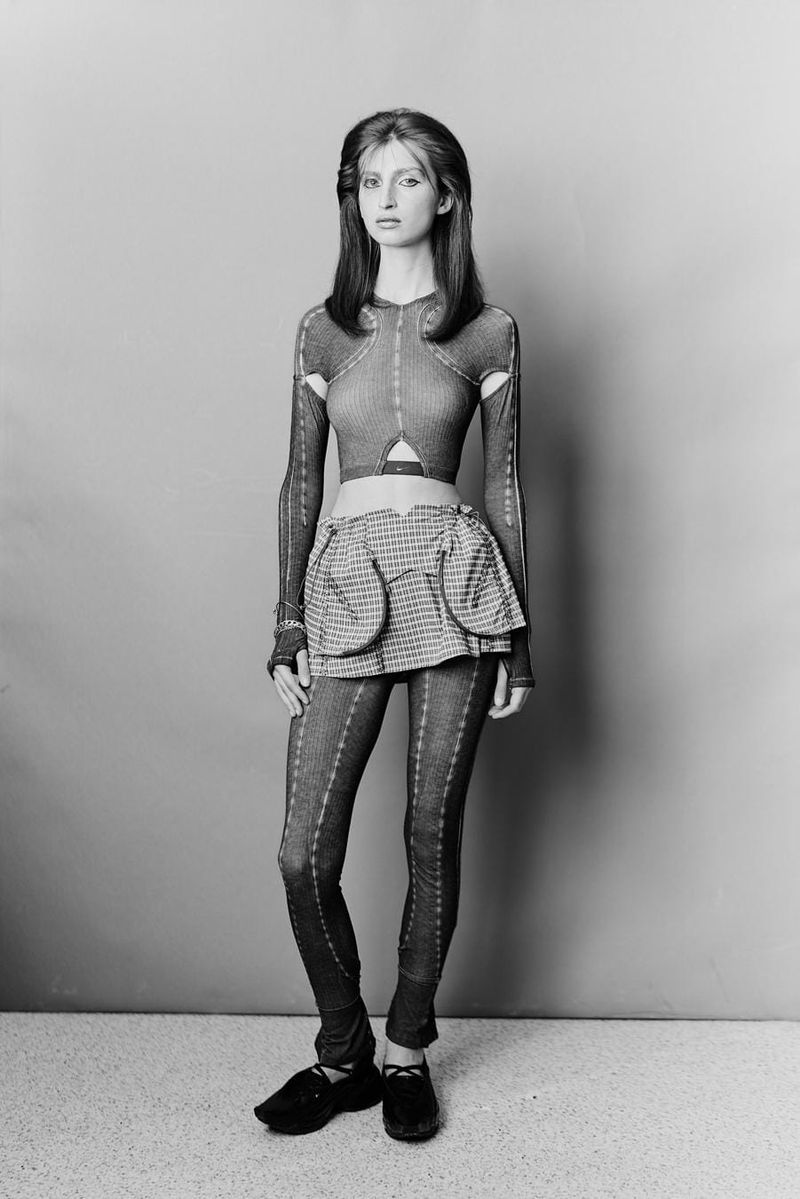 Model Emily Carmen wearing fitted patterned garments with cutouts against a neutral studio backdrop.