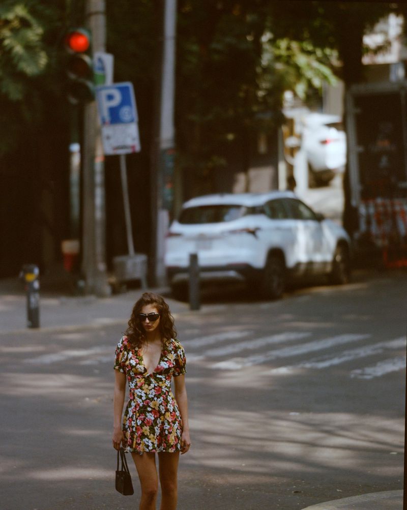 Model wearing a floral print mini dress and sunglasses walking on a city street for Reformation Spring 2026