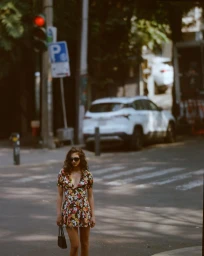 Model wearing a floral print mini dress and sunglasses walking on a city street for Reformation Spring 2026