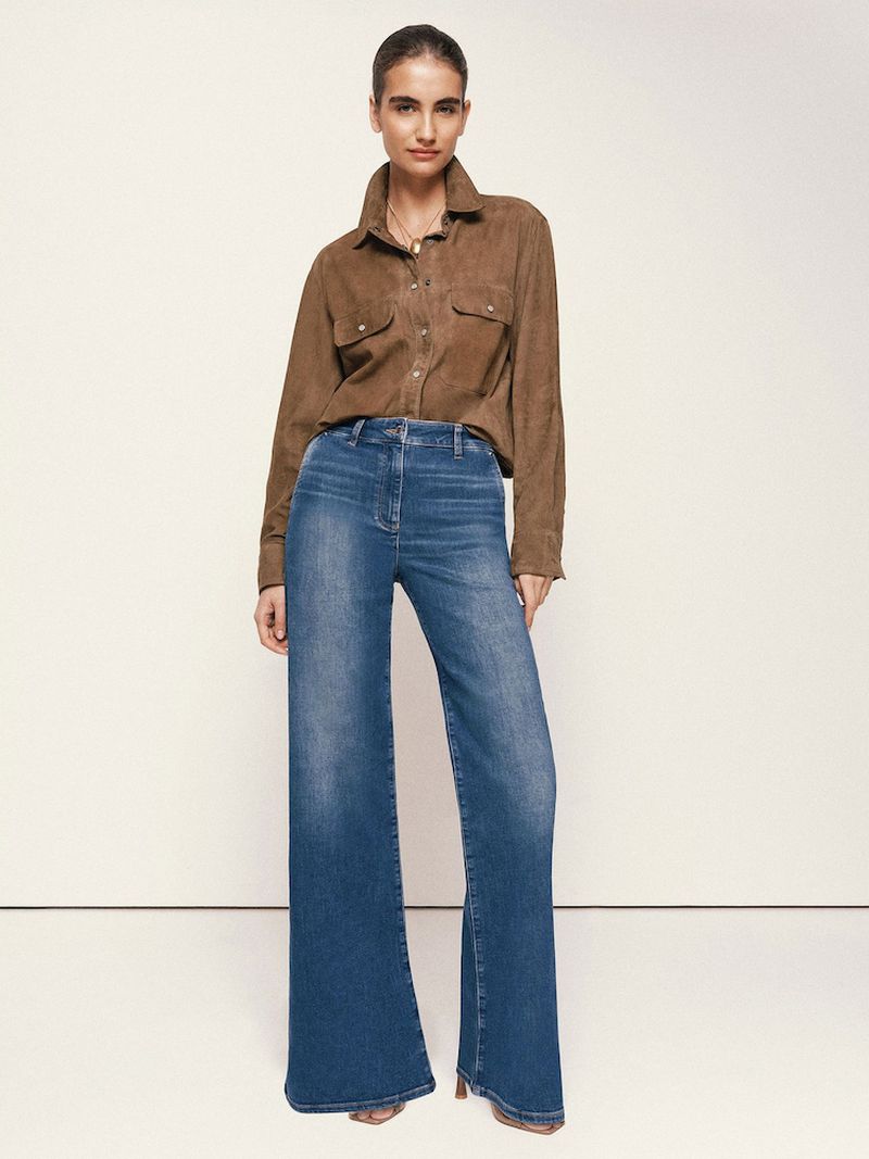 Model wearing a brown button-up shirt and blue wide-leg denim jeans against a plain neutral background.