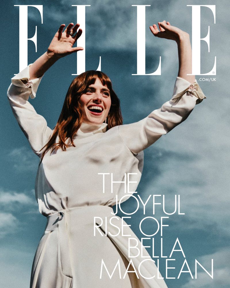 Elle Magazine cover featuring Bella Maclean wearing a white dress, posing outdoors against a blue sky with light clouds, smiling joyfully.