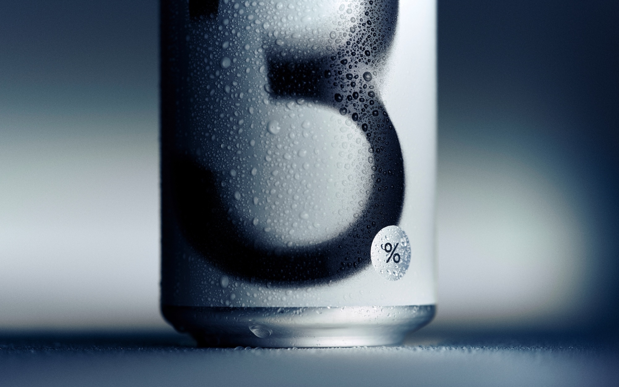 Close-up of a condensation-covered beverage can featuring bold typography against a cool, softly lit background.