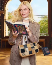 Elle Fanning holding a book and wearing a plaid blazer and patchworked leather shoulder bag inside a library