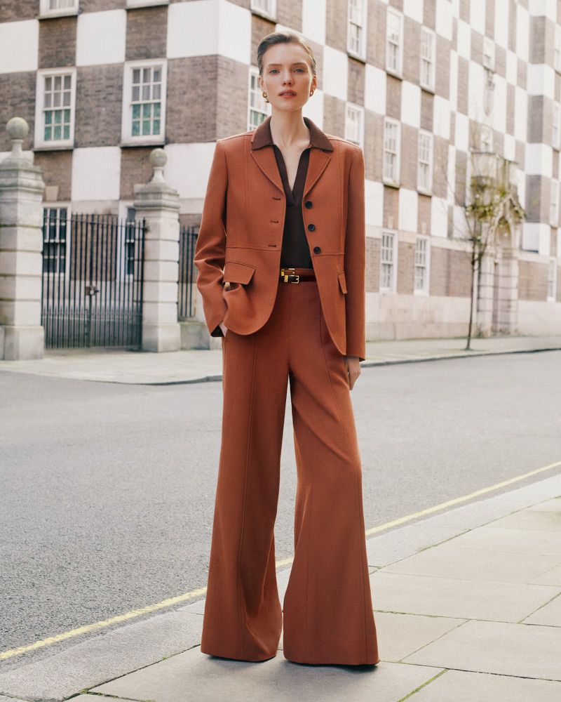 Model standing on a city street wearing a rust-colored trouser suit for the ME+EM May Campaign.
