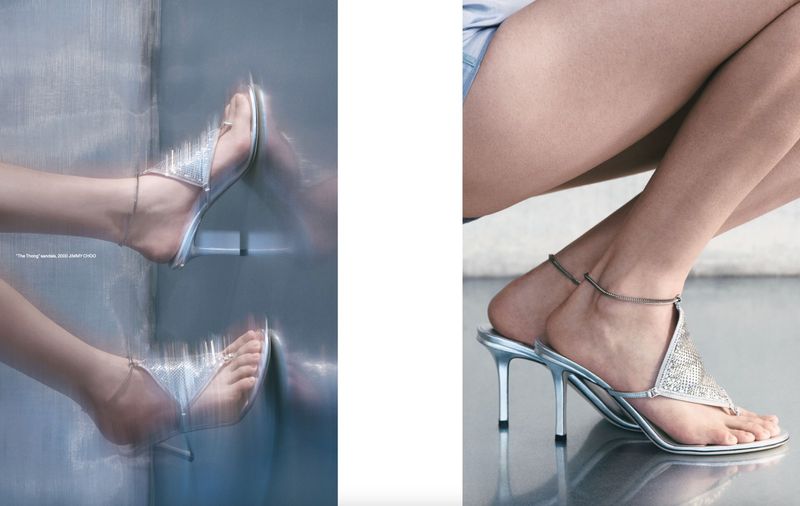 Close-up of a fair-skinned model in light blue shorts wearing silver high-heeled sandals with jeweled straps, photographed indoors.