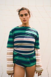 Model Jill Kortleve wearing layered striped shirts against a goal net background for Vogue España