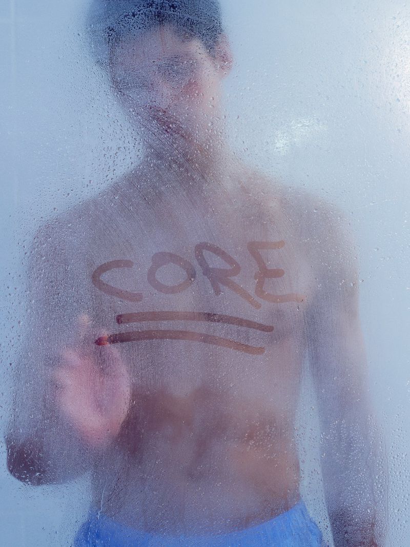 An adult man is seen behind a steamy glass surface, on which the word 'CORE' is written with two lines underneath.