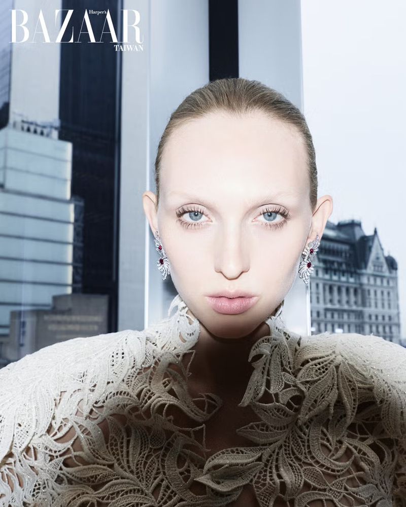 Model Delilah Koch wearing a white lace dress with ornate earrings against a city building exterior background