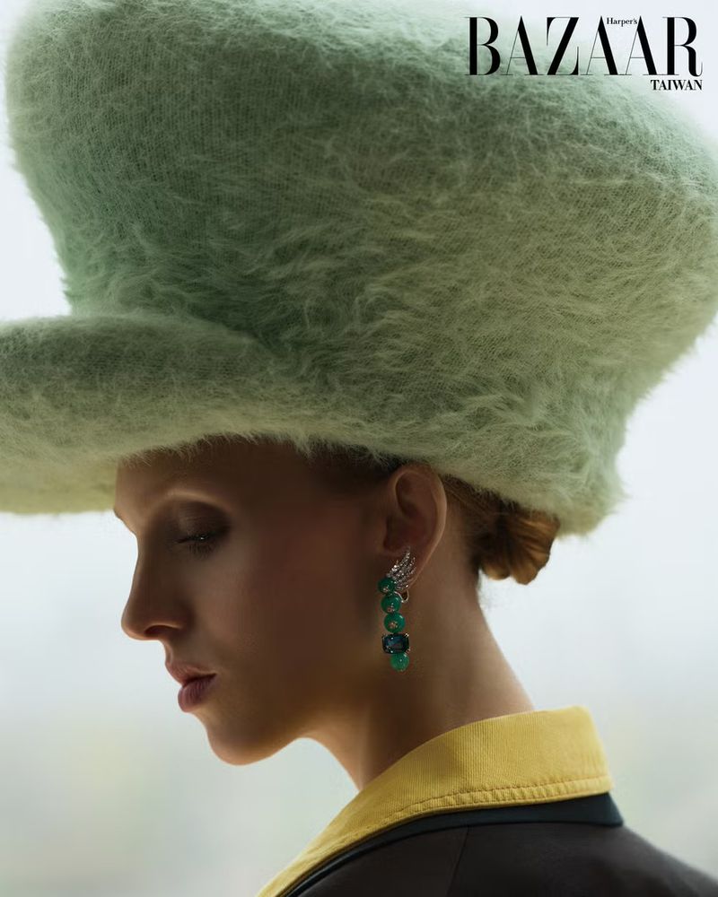 Model Delilah Koch wearing a large green fuzzy hat and green beaded earrings for Harper's Bazaar Taiwan