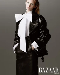 Model Delilah Koch in a black leather jacket and white bow blouse against a grey seamless background for Harper's Bazaar Taiwan.