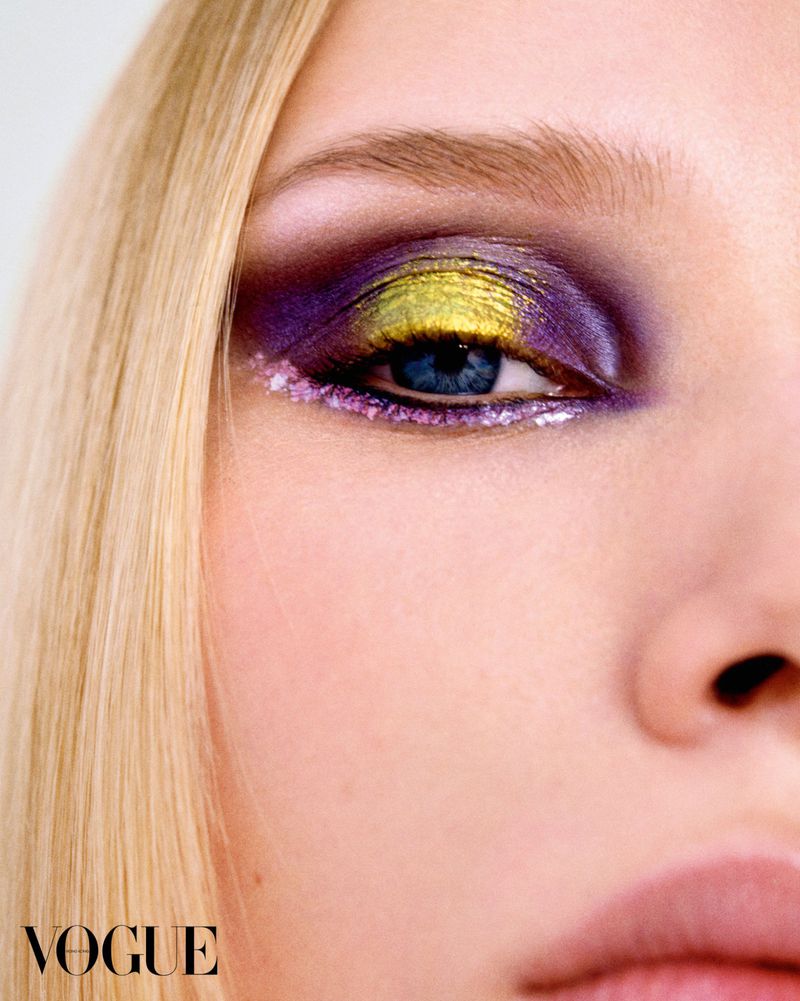 Close-up portrait of a blonde woman with metallic gold and purple eye makeup for Vogue Hong Kong.