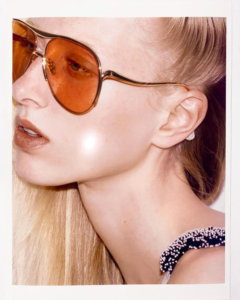 Close-up portrait of a female model wearing tinted orange aviator sunglasses and an embroidered dark strap for M Le magazine du Monde