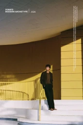 Model standing on white stairs against a modern yellow building exterior for Massimo Dutti Modern Archetype