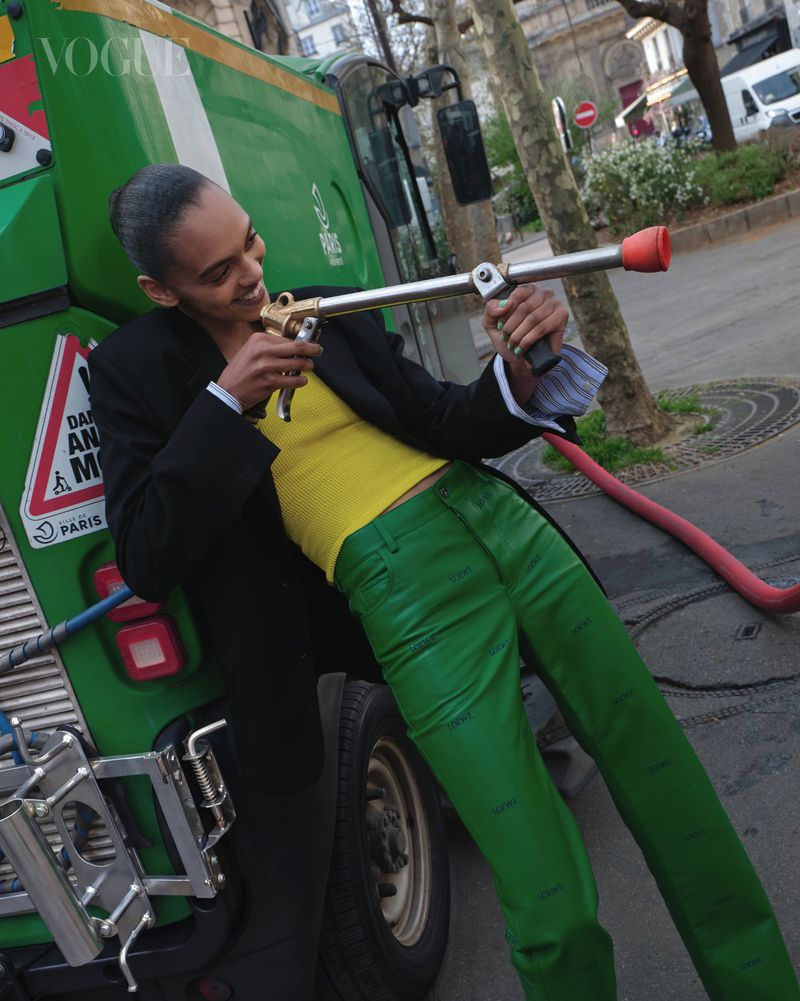 Model holding a high-pressure hose handle while posing in front of a green municipal vehicle outdoors