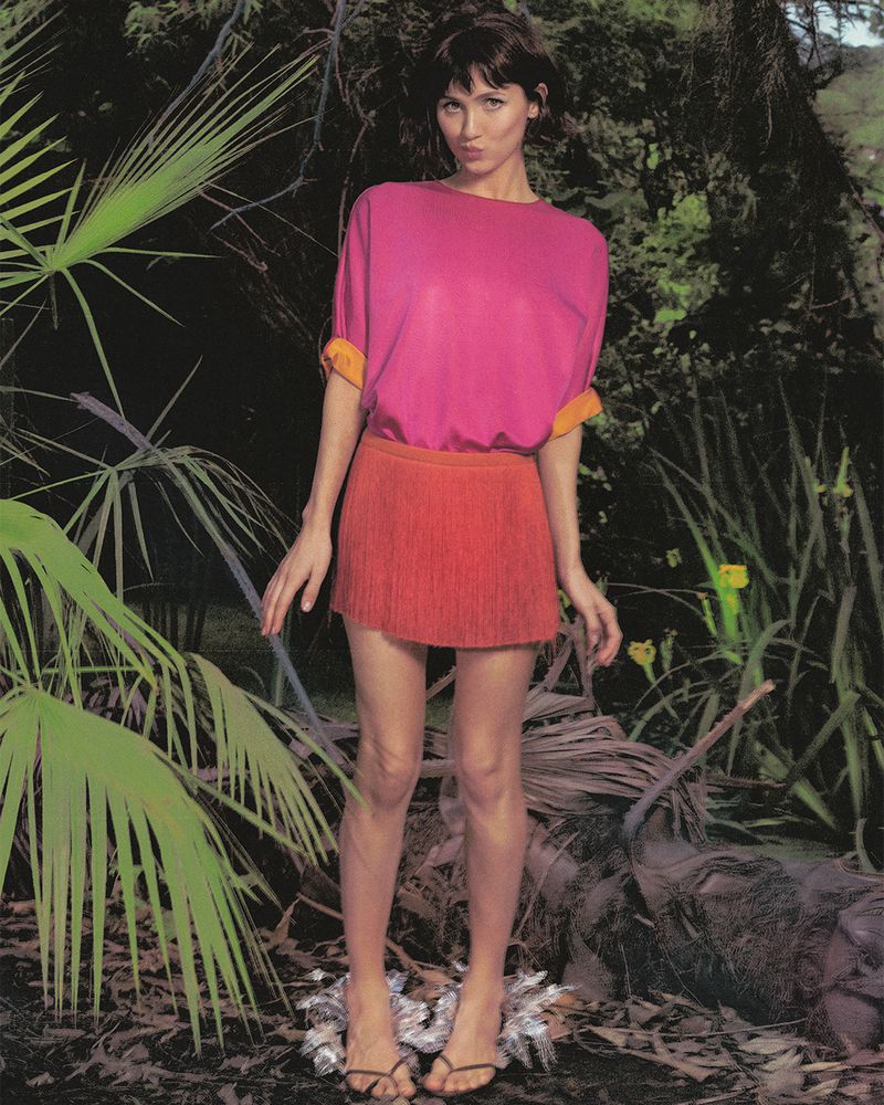 Maude Apatow posing outdoors in a pink top and red skirt surrounded by lush tropical foliage for Who What Wear.