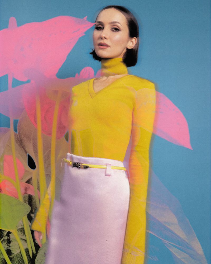 Maude Apatow wearing a yellow top and pink skirt against a blue floral background for Who What Wear