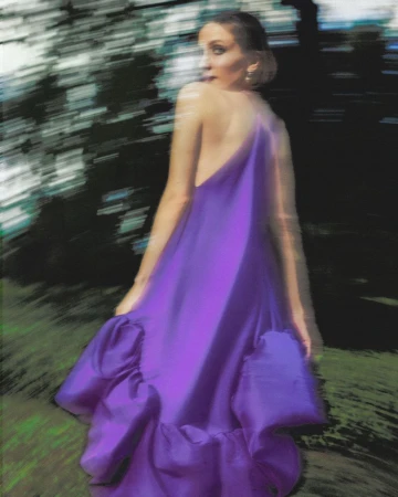 Maude Apatow wearing a long purple gown in a motion-blurred outdoor setting for Who What Wear