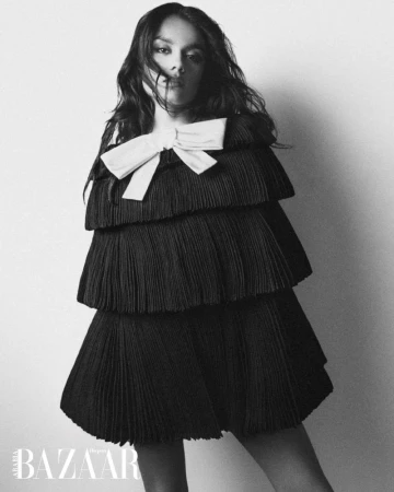 Simone Ashley in a black tiered dress with a white bow, shot by JuanKr for Harper's Bazaar Arabia.