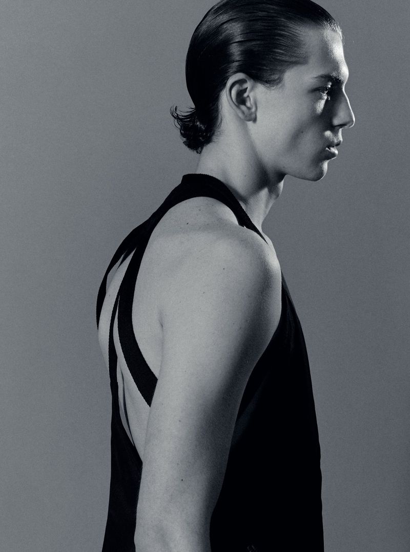 Profile portrait of a male model in a black tank top against a grey studio backdrop captured by Isaac Anthony.