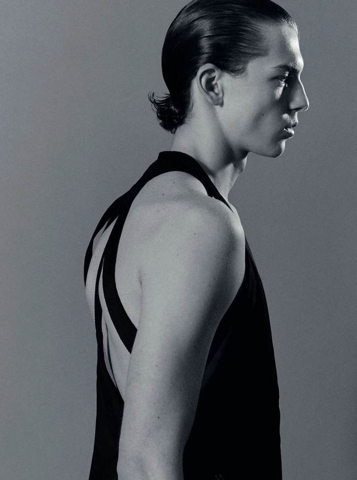 Profile portrait of a male model in a black tank top against a grey studio backdrop captured by Isaac Anthony.