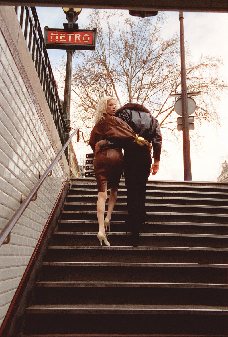 Two models walking up tiled outdoor stairs past a Metro sign, captured from a low angle.
