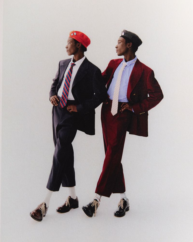 Two Black male models wearing tailored suits and berets against a white seamless studio backdrop for Latest Magazine.