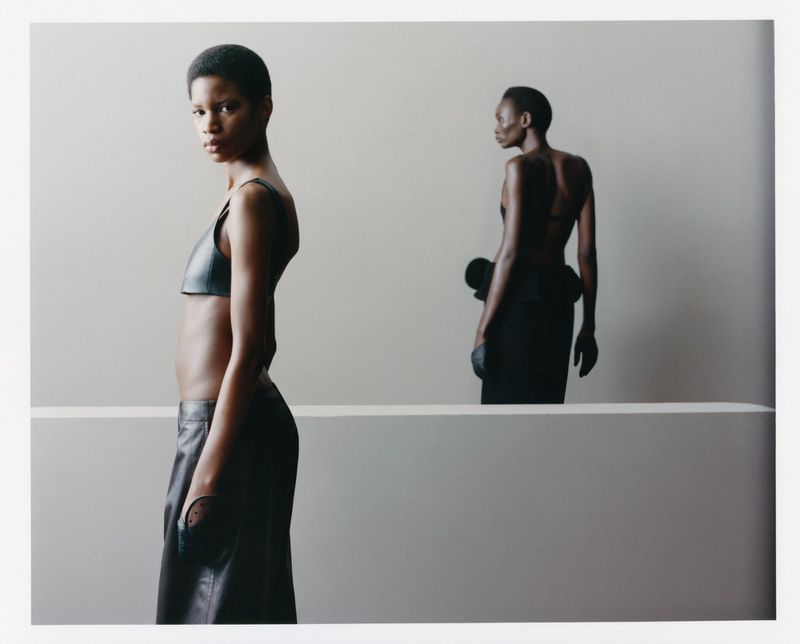 Two black female models in dark attire against a minimal grey backdrop for SSAW Magazine.