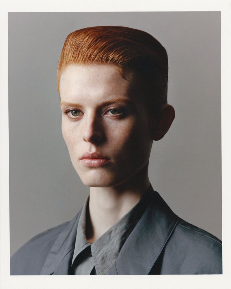 Portrait of a model with short red hair and a dark grey shirt against a plain grey background for SSAW Magazine