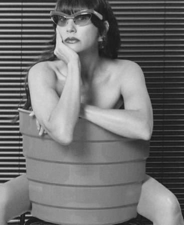 Rashida Jones wearing cat-eye sunglasses seated in a ribbed plastic tub for the Good Friends project by MARFA.