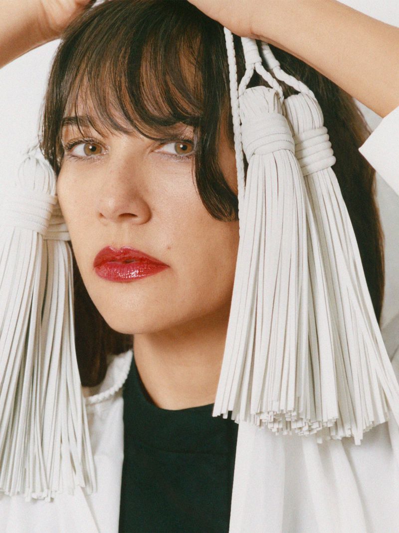 Portrait of actress Rashida Jones wearing large white tassels framing her face for MARFA Good Friends project.