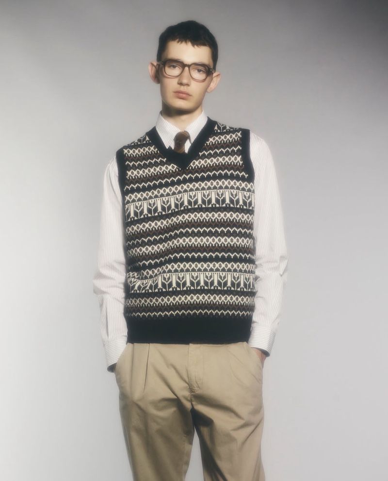 Model wearing patterned sweater vest and glasses over white shirt for Aspesi S/S 26 campaign