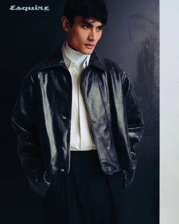 Man wearing a dark leather jacket, white turtleneck, and striped shirt against a dark background for Esquire Australia