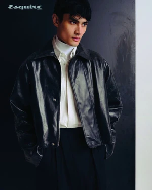 Man wearing a dark leather jacket, white turtleneck, and striped shirt against a dark background for Esquire Australia