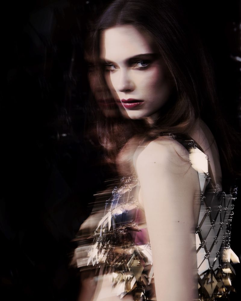Portrait of a woman wearing a metallic embellished top against a dark background with multiple exposure blur effects.