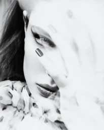 Close-up black and white portrait of a model with winged eyeliner and hand partially covering face for Numero Netherlands
