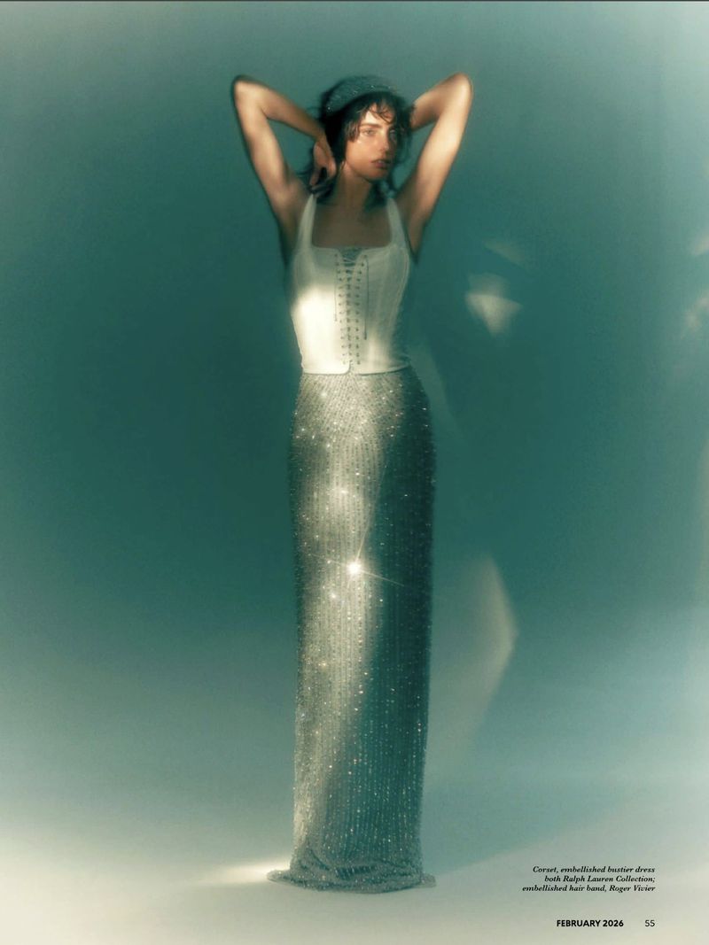 Model Marinet Matthee wearing a white corset and sparkling silver skirt posing against a teal gradient background.