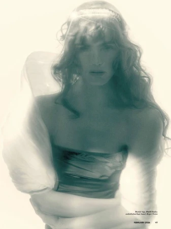 Model with long wavy hair wearing a strapless top and embellished hair band in a soft focus editorial portrait.