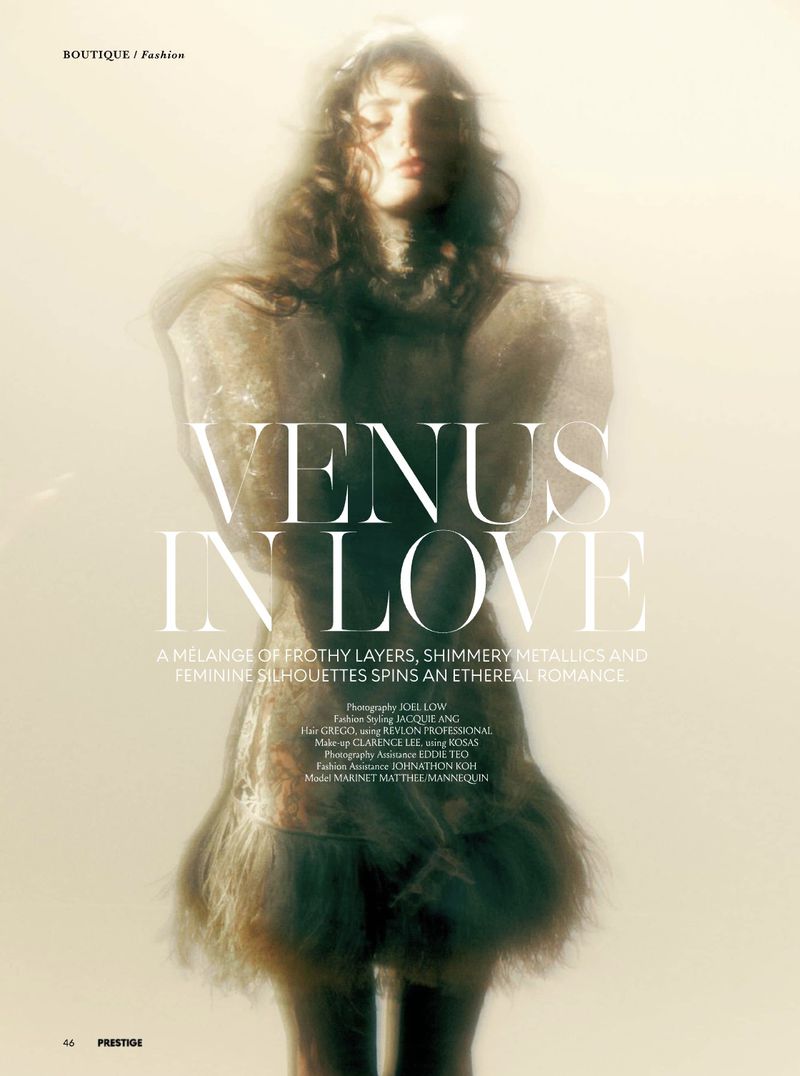 Model in textured metallic dress with feathered hem standing against a glowing golden background for Prestige Magazine Asia