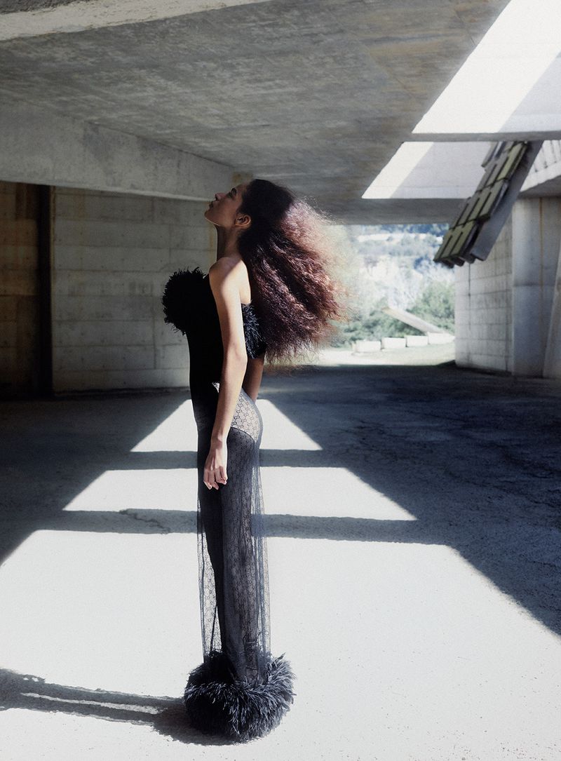 Model in textured black evening dress posing under concrete architecture for Vanity Fair Italia