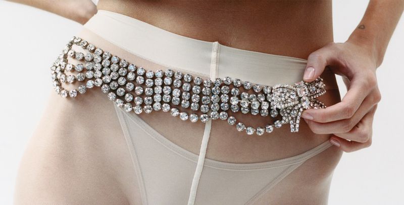 Waist shot of a woman wearing a rhinestone belt, accentuating her silhouette with a decorative bow and transparent material.