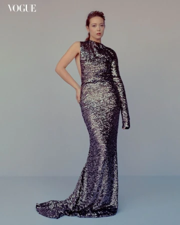 A woman posing in a one-shoulder sequin gown for a Vogue fashion editorial, set against a neutral background, with the 'Vogue' logo visible.