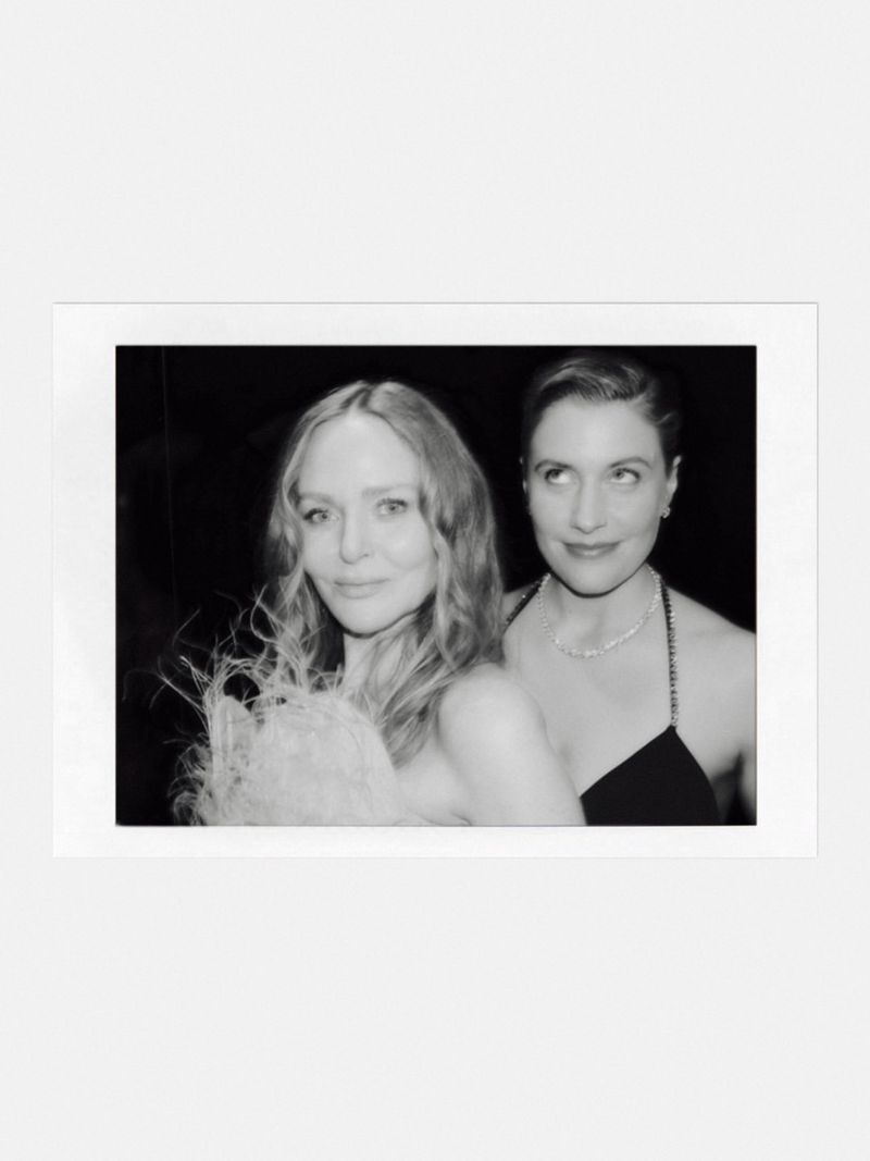 Two women posing together in a monochrome polaroid frame with a dark background.