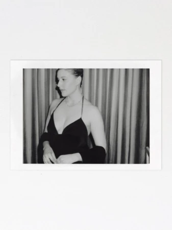Black and white polaroid photograph of a woman wearing a halter-neck dress against a curtained backdrop.